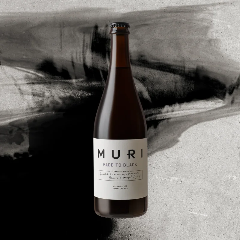 a bottle of MURI Fade to Black against black brushstrokes on concrete