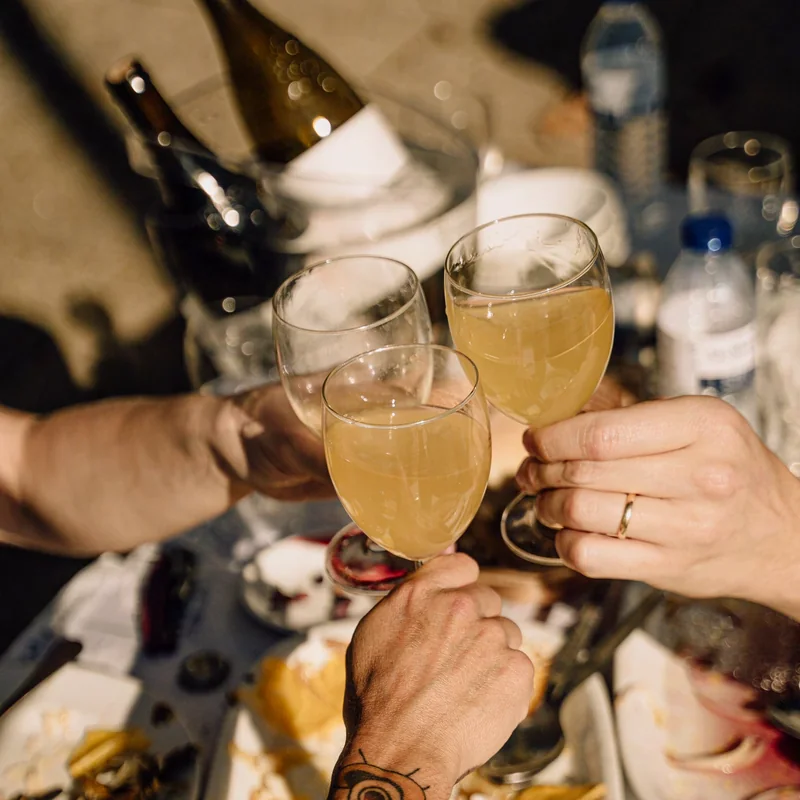 glasses raised over a table of food