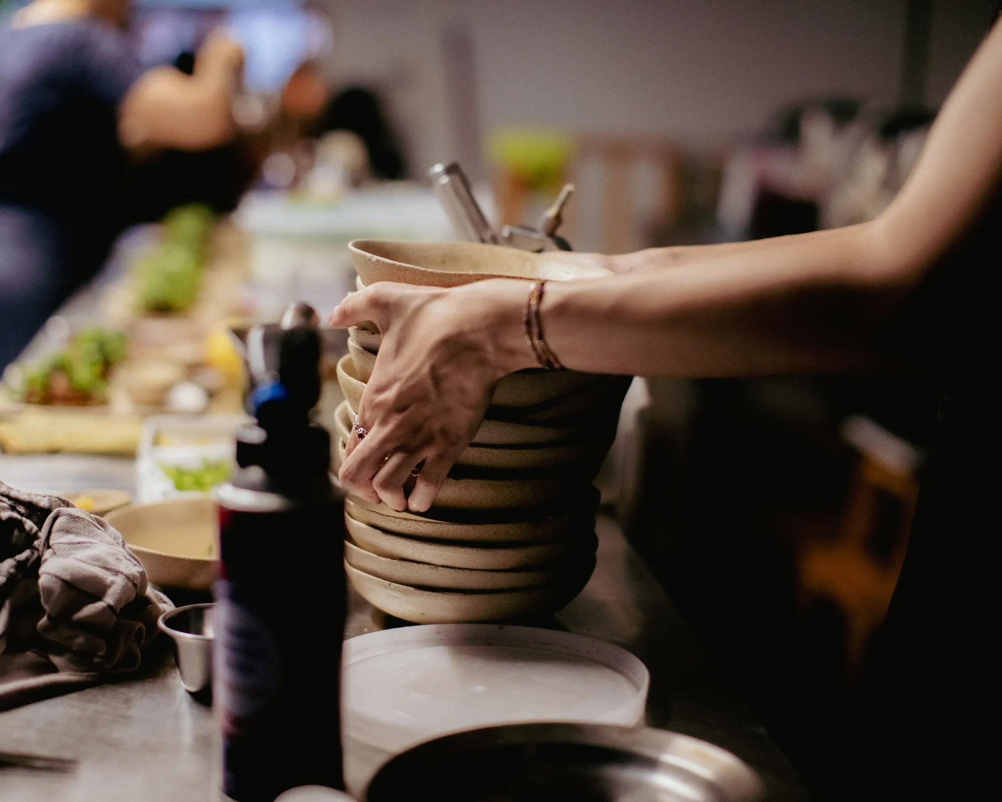 hands stacking clean bowls at the pass in the venn kitchen