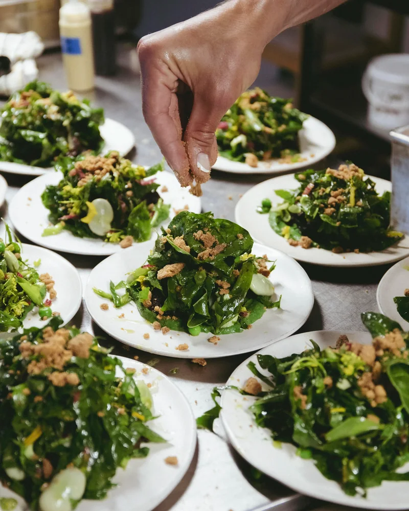 Kitchen team plating multiple dishes for a group at Venn Canteen